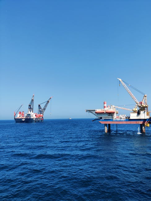 Offshore oil platforms with cranes operating in the Persian Gulf under a clear blue sky.